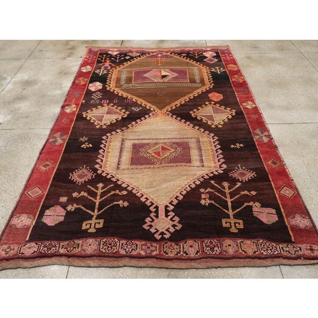 This mid-20th century Turkish Anatolian tribal carpet, exemplifies the expressive and symbolic artistry characteristic of...