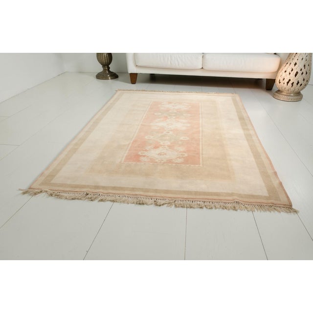 This is a vintage Turkish Oushak rug from the Mid 20th Century. The piece was hand-knotted.