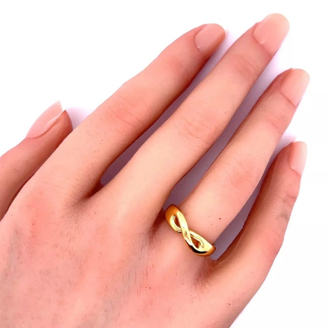 This elegant authentic band ring is by Tiffany & Co. from the Infinity Collection. Crafted from 18k yellow gold with a...