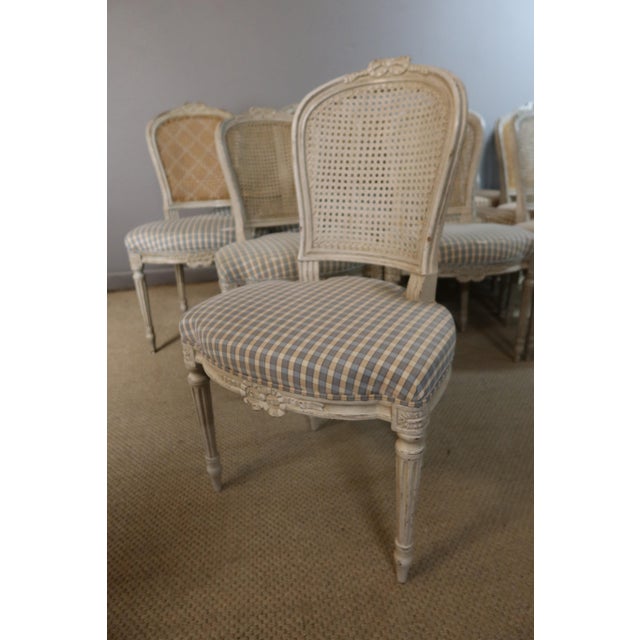 Set of 14 Louis XVI style carved and painted wooden chairs, 20th century. The backs are caned with varying weaves, and the...