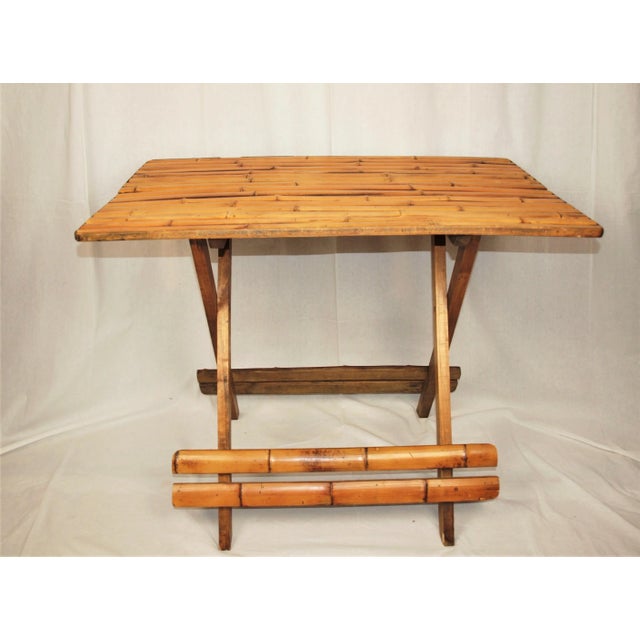 A mid-century folding natural bamboo table. Unusual table in that it folds flat from the center. Natural bamboo with a...