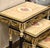 Elegant set of three French-style nesting tables featuring sophisticated black frames accented with luxurious gold leaf...