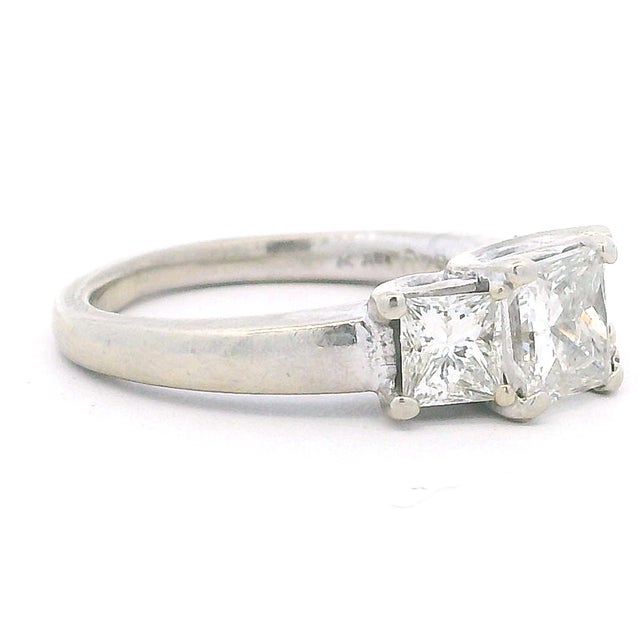 A clean and timeless three-stone diamond ring with a modern edge. This piece features three well-matched princess-cut...