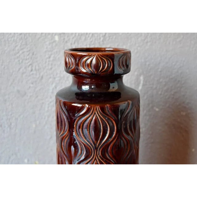 with its dark brown enamel, decorated with repetitive geometric shapes in relief, its roll shape and its beautiful...