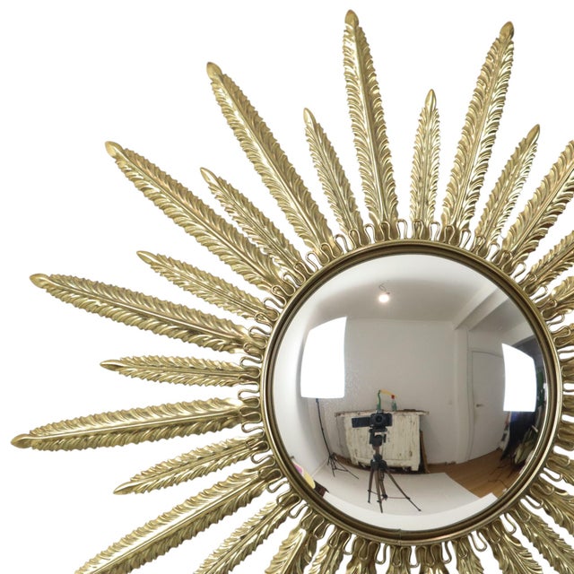 A stunning mid-century sunburst mirror made of copper-plated metal and wood, featuring a convex mirror. This fantastic...