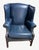 A handsome pair of traditional wingback chairs upholstered in rich navy blue leather, featuring classic rolled arms, brass...