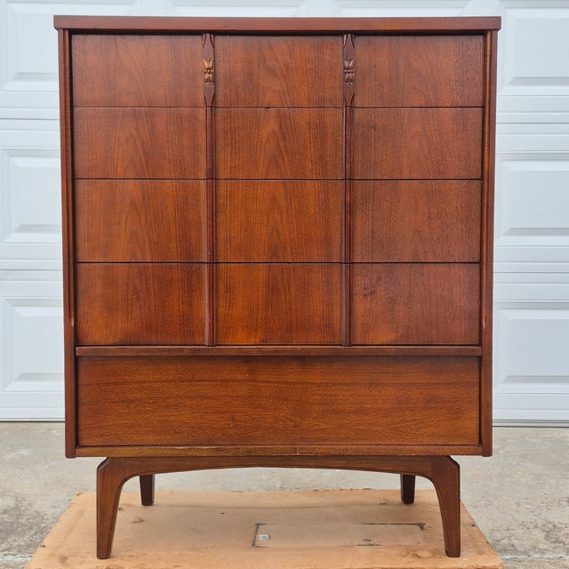 This is a handsome vintage mid century modern walnut veneer tall chest of drawers or highboy dresser. The dresser is...