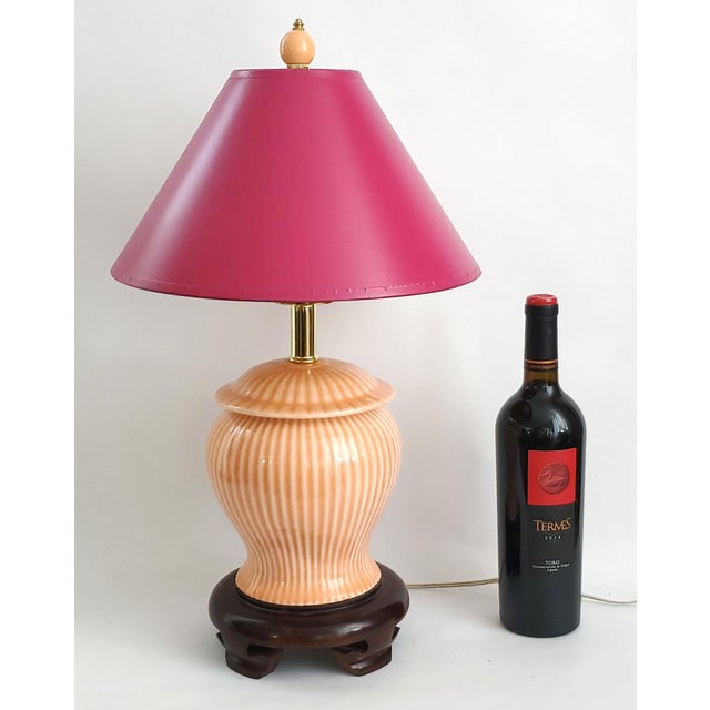 Offering a small Chinese ginger jar table lamp with wood base and vintage magenta cardboard shade, circa 1980s. This...