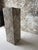 A striking rectangular pedestal clad in richly variegated gray stone arranged in a bold herringbone pattern. Layers of...