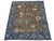 An olive-brown field and deep blue floral border distinguish this handmade Oushak wool rug. Scattered blossoms and angular...