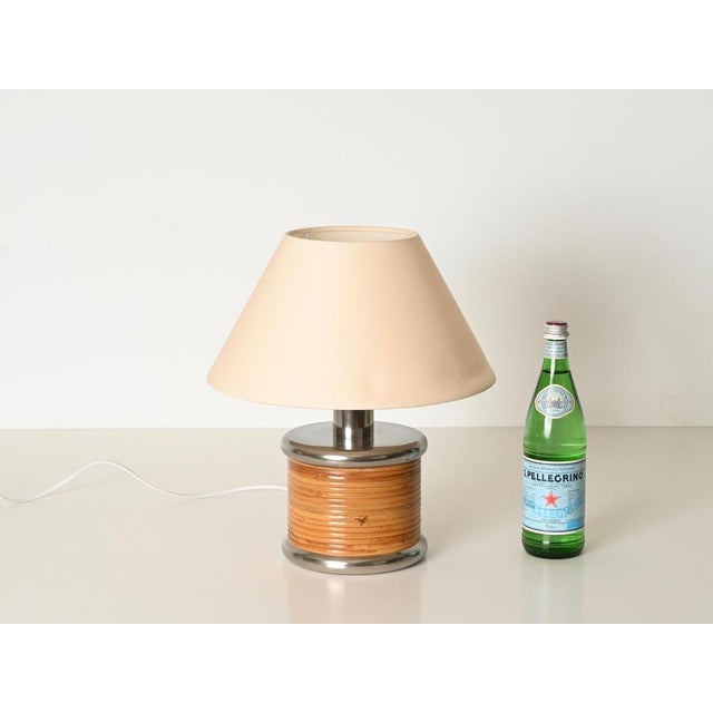 Gorgeous mid-century table lamp entirely crafted from curved rattan and chrome-plated metal, completed with a cotton...