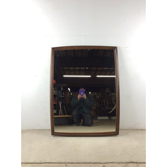 This mid century modern wall mirror features hardwood beveled edge frame, original walnut finish, unique oblong shape, and...
