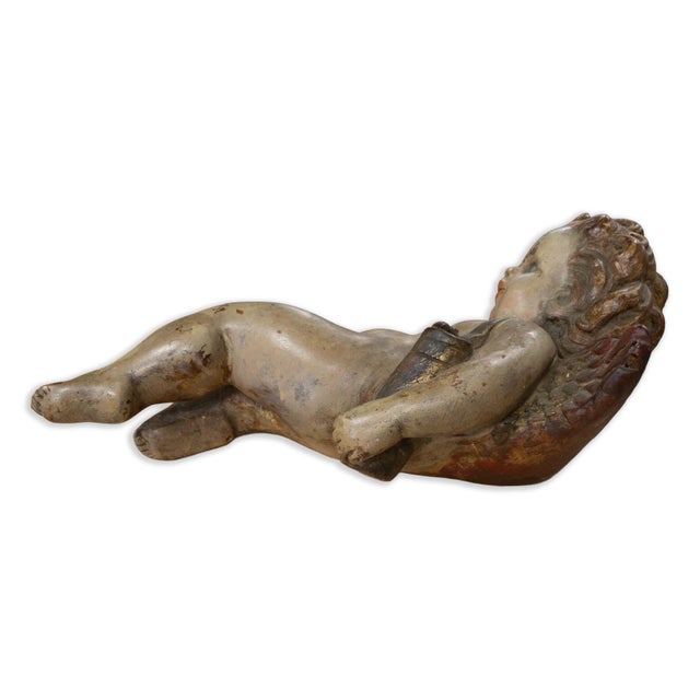 A finely modeled Italian Baroque style reclining cherub, hand-painted and dating to the 19th century. Rendered in ceramic...