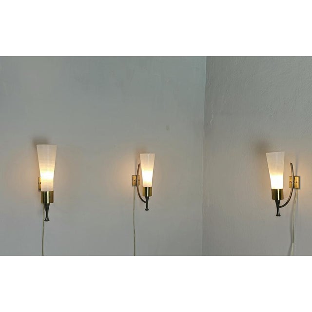Set of 3 wall lamps produced in Italy in the 1950s. Each single wall lamp was built with a brass structure that supports a...