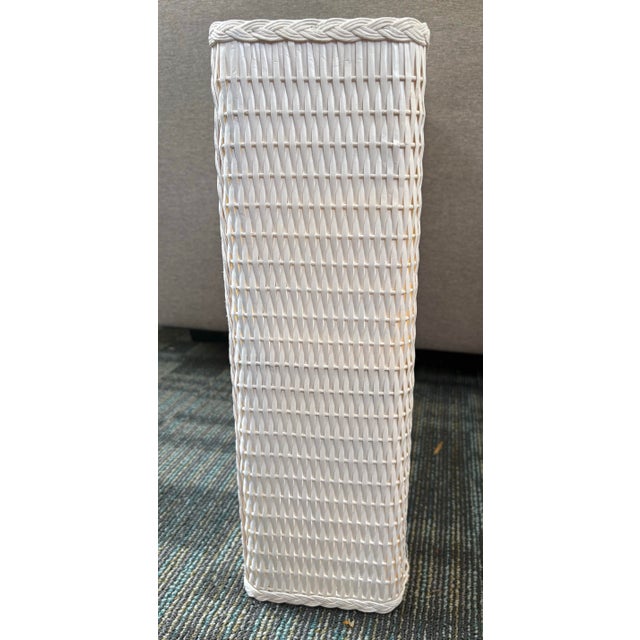 Charming vintage white wicker two-tier wall shelf with woven rattan-look sides and back panels, finished with decorative...