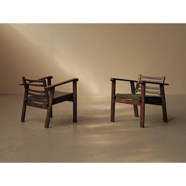 Pair of solid oak armchairs with a low, understated profile and clean lines. The simple frame is made of straight uprights...