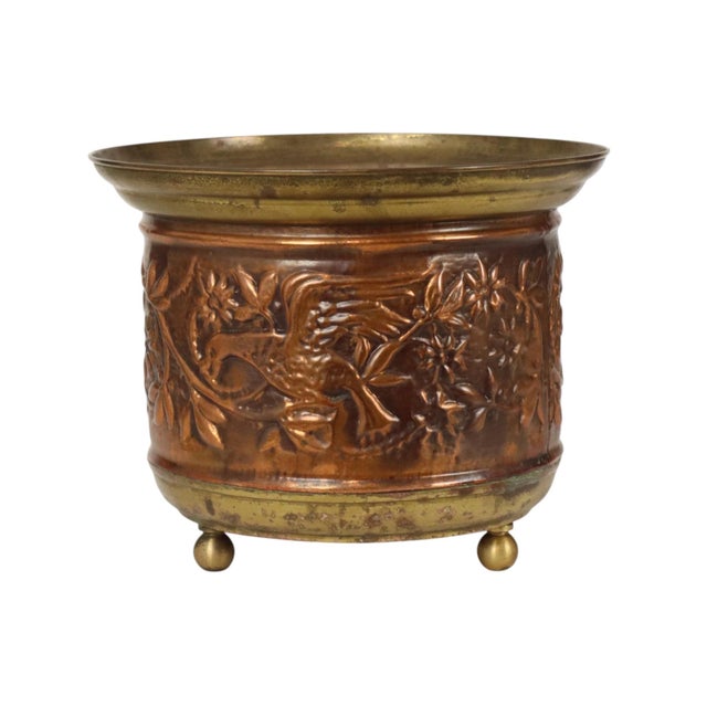 A charming vintage repoussé flower pot or cachepot crafted from red copper and brass, featuring elegant relief decoration...