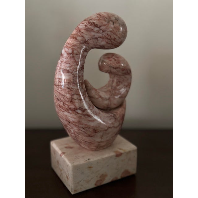 This is a decorative sculpture made of pink marble with natural marbling patterns. The sculpture features a spiral design...