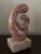 This is a decorative sculpture made of pink marble with natural marbling patterns. The sculpture features a spiral design...