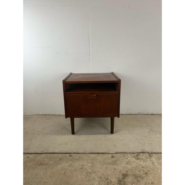 This danish modern nightstand features solid teak construction, removable tapered legs, and drop front design with...