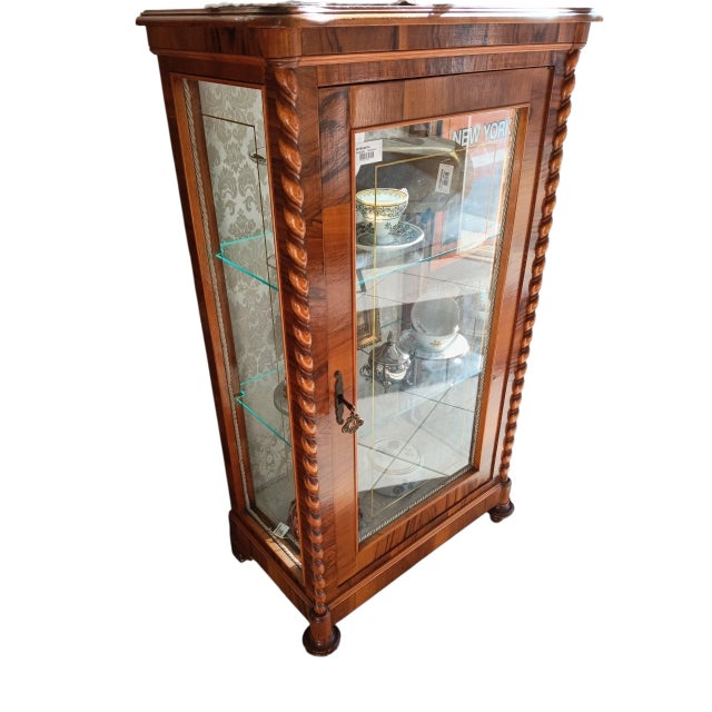 Single-door display cabinet with glass shelves and damask bottom.
