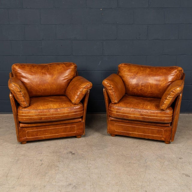A characterful pair of leather club armchairs, produced in the manner of roche bobois and dating to the late 1970s–1980s....