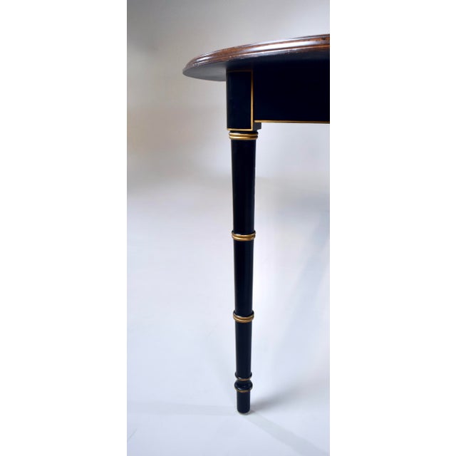 An elegant oval lacquered dining table by Baker Furniture with distinct Maison Jansen Design elements in the tapered faux...