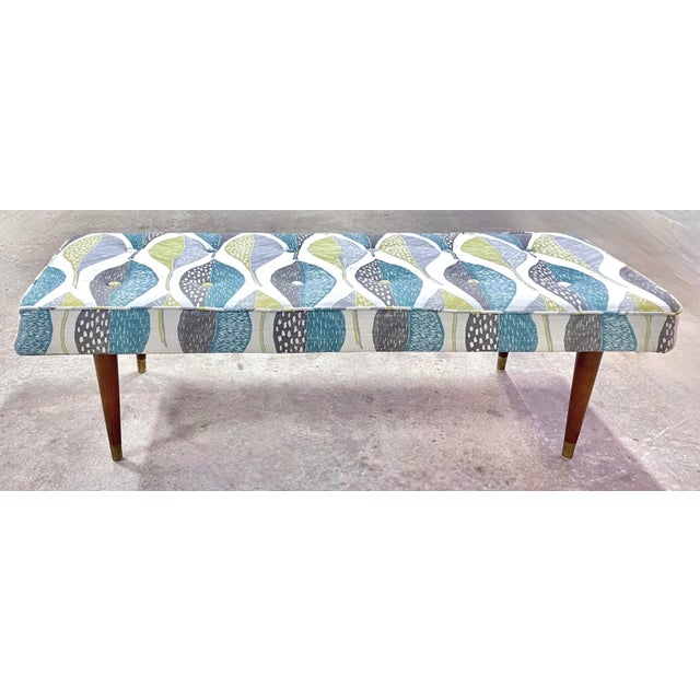Mid-Century Modern leaf pattern upholstered bench with tapered legs and brass feet. Button tufted abstract batik leaf...