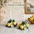 Charming vintage ceramic candlesticks featuring hand-painted lemons, lemon blossoms, and lush green foliage in a vibrant...