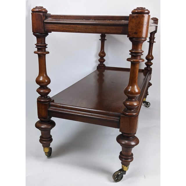 French mahogany server or dumbwaiter, circa 1830. This two tier dumbwaiter with turned columns stands on turned legs with...
