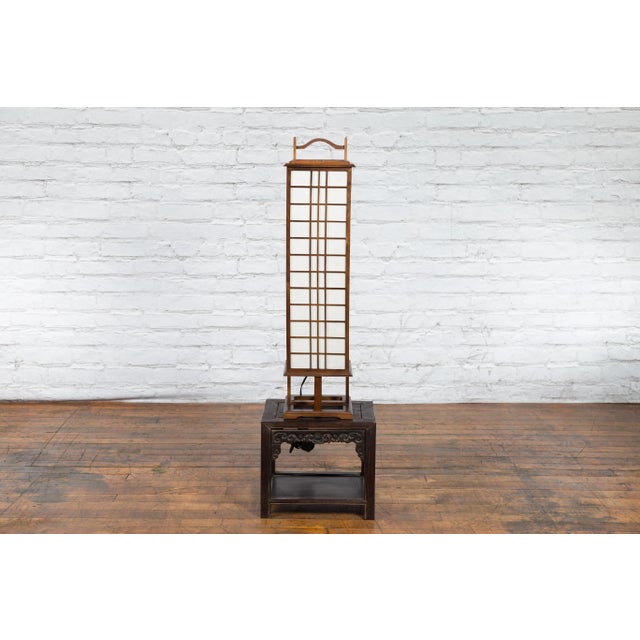 A tall vintage Japanese square shaped wooden table lamp from the mid 20th century, with rice paper panels securing a light...