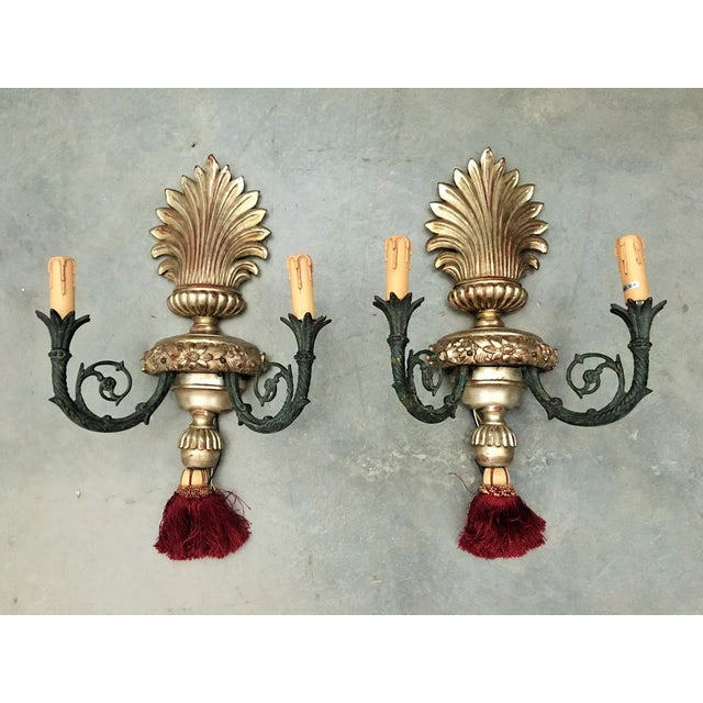 Pair of bronze two-lights Caldwell sconces with urn-shaped backplate. Original patina. Beautiful and elegant pair of...