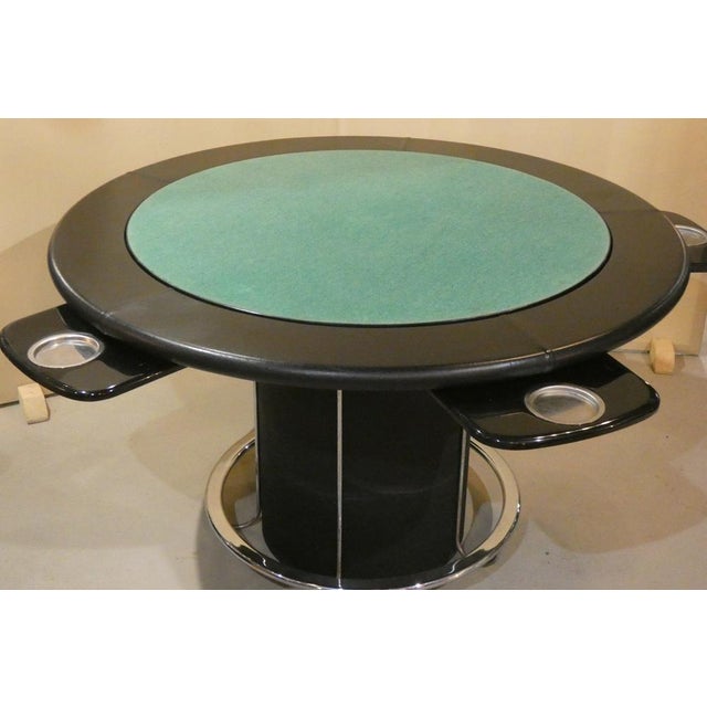 Game table edged in leather, with black painted steel body and chromed steel footboard. Located at the center of the table...