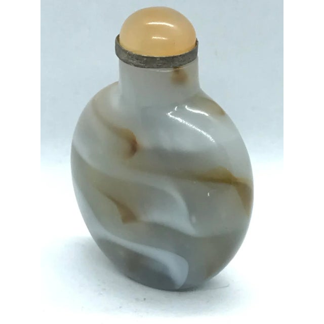 The Sandwiched Glass bottle has a flattened round form. The light gray glass is suffused with striations in alternating...