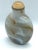 The Sandwiched Glass bottle has a flattened round form. The light gray glass is suffused with striations in alternating...