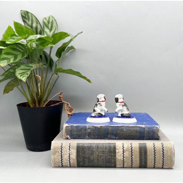 Delightful pair of antique porcelain spaniel dog figurines perched atop rich cobalt blue cushions with hand-painted gilt...