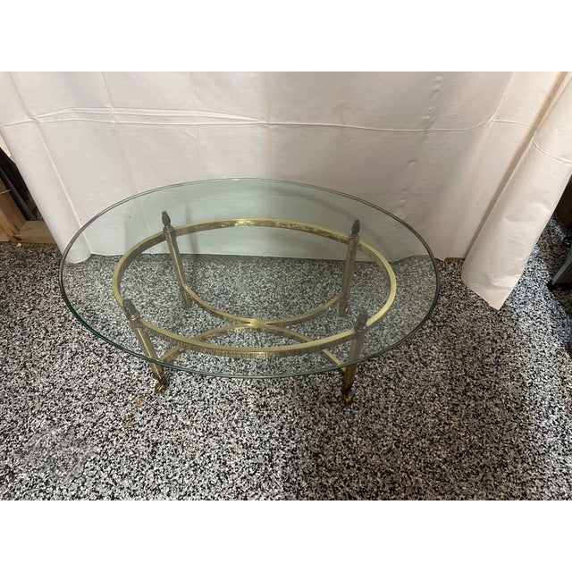 Vintage La Barge polished brass oval coffee table with bevelled glass top. Cross bars and decorative feet and top . Circa...