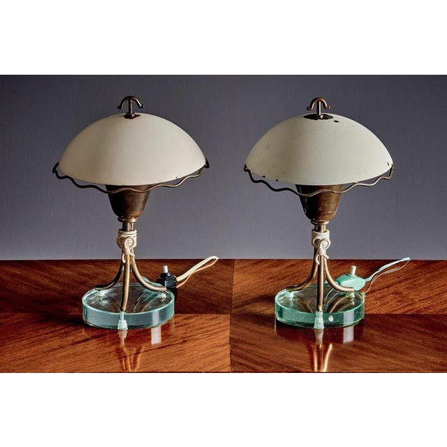 Elegant pair of Italian Mid-Century Modern table lamps, featuring off-white domed metal shades, patinated brass supports,...