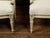 A pair of French Louis XVI style walnut settees from the early 20th century, with scrolling arm supports, fluted legs and...