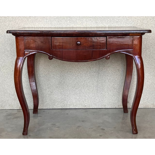 Having a rectangular top with bookmatched solid walnut boards above a case housing one-drawer, raised on square tapering...