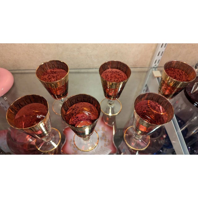 Wonderful set of six cocktail wine glasses in cranberry glass with clear stems and intricate gold overlay. I believe these...