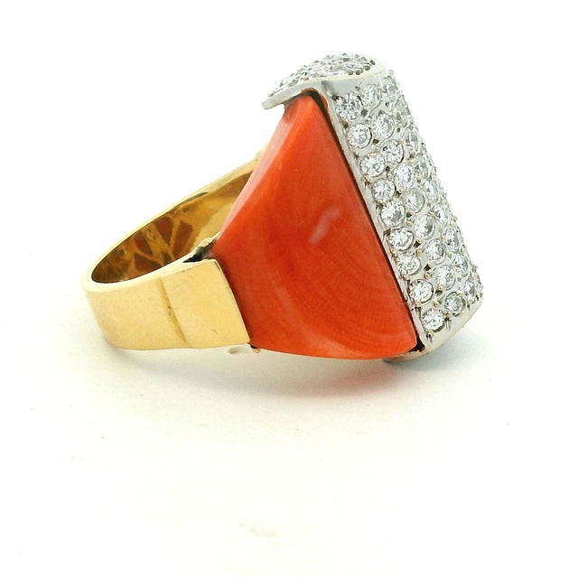 A bold 1970s cocktail ring crafted in 18K yellow gold, featuring two sculptural polished coral panels framing a dramatic...