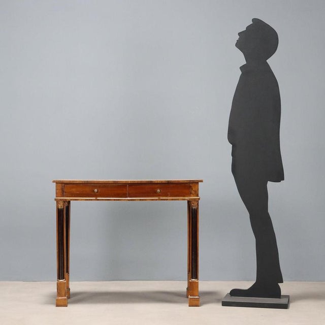 Empire walnut console table. Drawer in the lower section, four turned and ebonized half-column legs, carved and gilded...