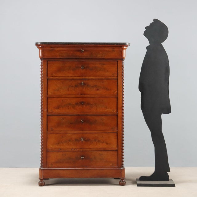 Charles X mahogany weekly chest. Black marble top, seven drawers, the first in the molded band beneath the top, and the...