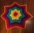 Large hand-crocheted star-shaped blanket in a full rainbow color progression, working outward from a red center through...