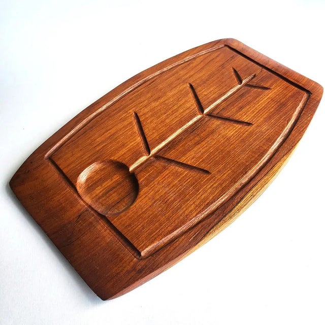 Offered is a vintage 1970s double-sided hand-carved surfboard shaped Teak wood meat-slicing board and snack tray. The...