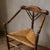 An antique corner chair crafted from solid wood with a handwoven rush seat. The design features a triangular seat, turned...