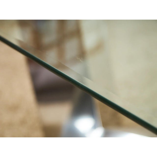 Dramatic sculptural dining table combining a substantial oval glass top with an architectural chrome base and cylindrical...