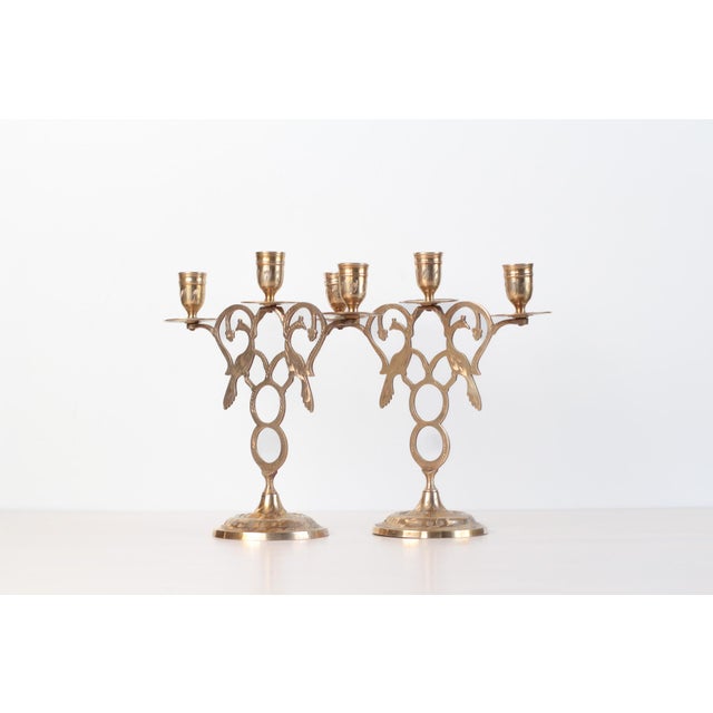 Vintage matching pair of brass three-arm candelabras with pierced filigree bodies featuring peacock and scrolling...