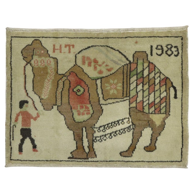 A cute small Turkish Pictorial Camel rug depicting a man pulling a large camel. Its also dated 1983 Measures: 2'2'' x 3'.